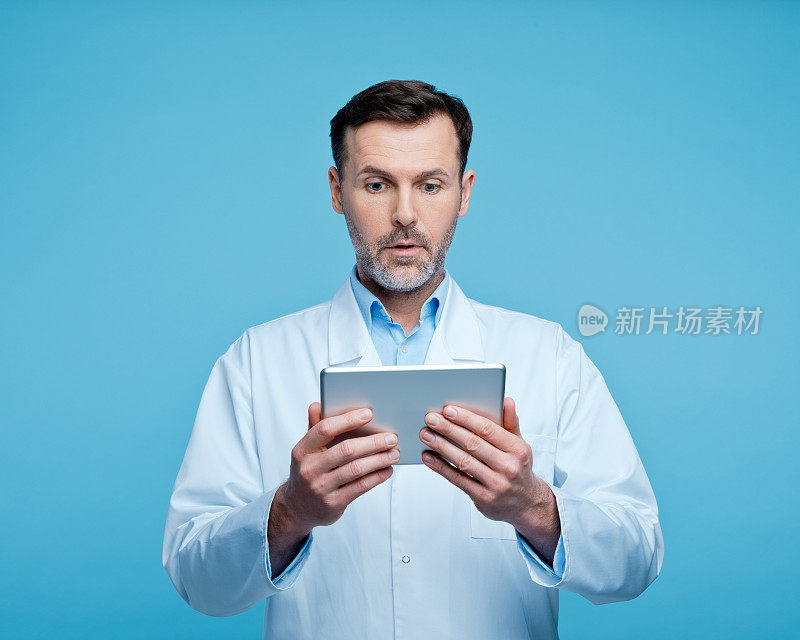 惊讶的男医生拿着数码平板电脑的肖像