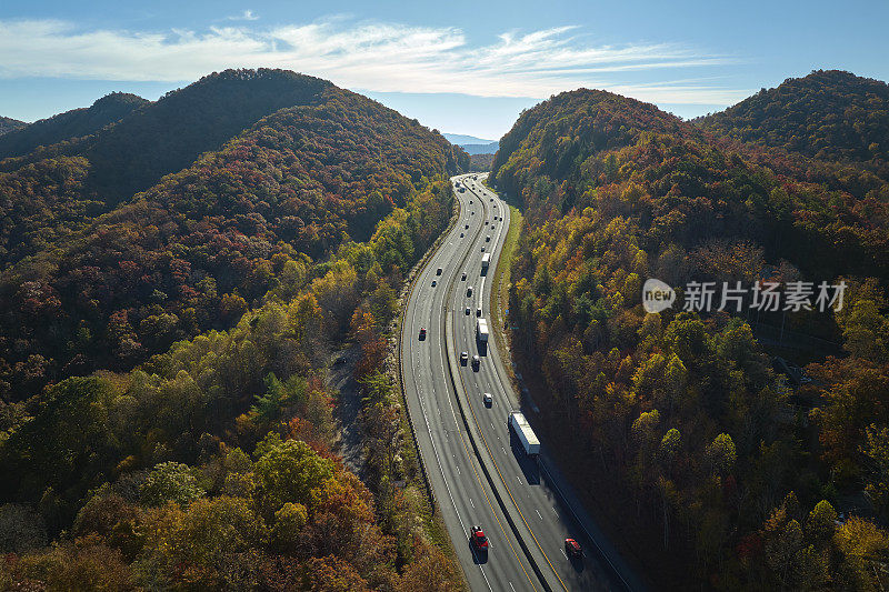 金秋时节，北卡罗莱纳州I-40高速公路穿过阿巴拉契亚山脉，通往阿什维尔，沿途行驶着快速行驶的卡车和汽车。州际运输概念