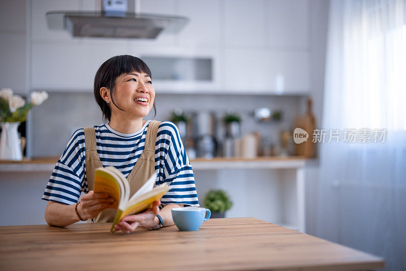 亚洲女性在家里放松，看书，喝酒