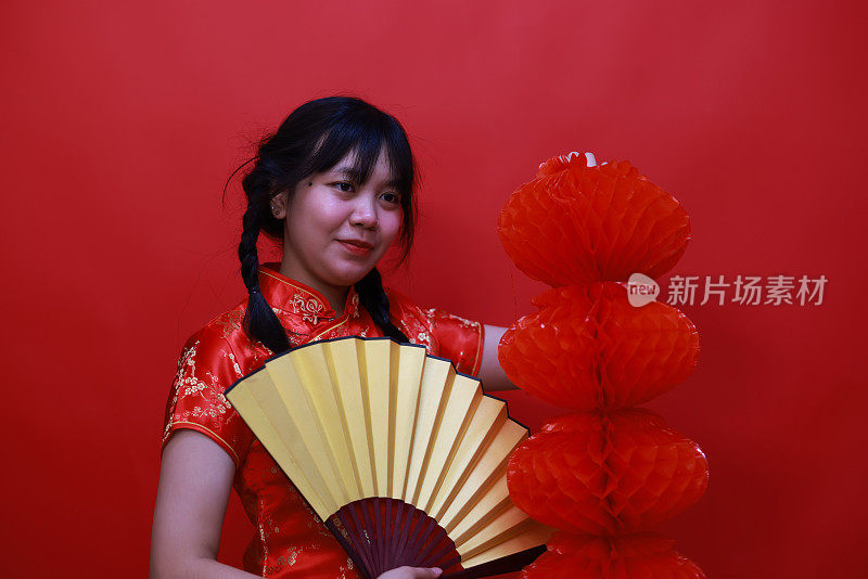 一个打着红灯笼和黄扇子的欢呼的女孩在摄影棚的中国新年节日概念