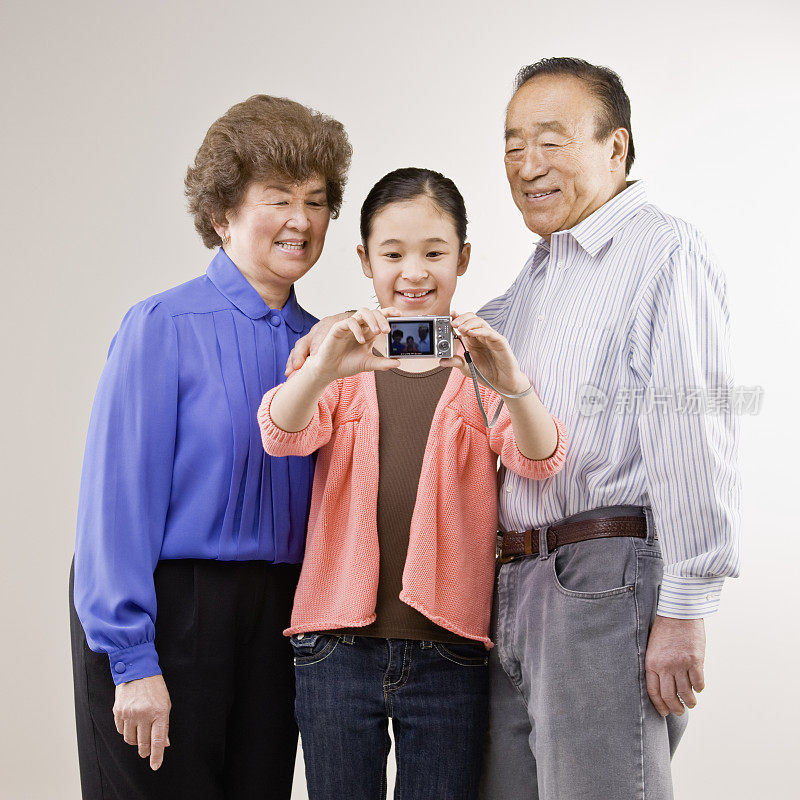 祖父母和孙女摆姿势用数码相机自拍