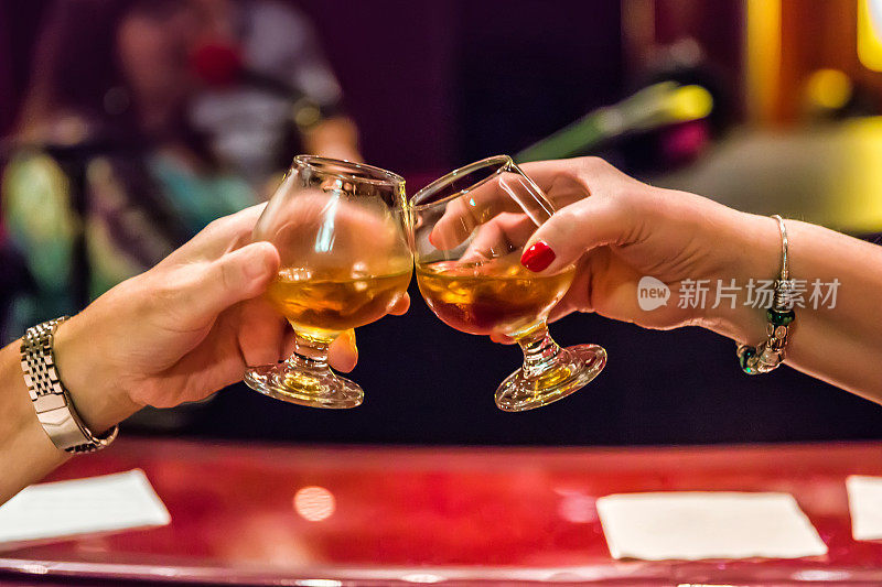 两个女人的手在酒吧碰杯。