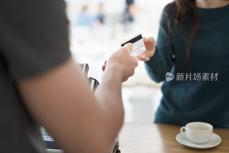 一个女人在咖啡店用信用卡付账