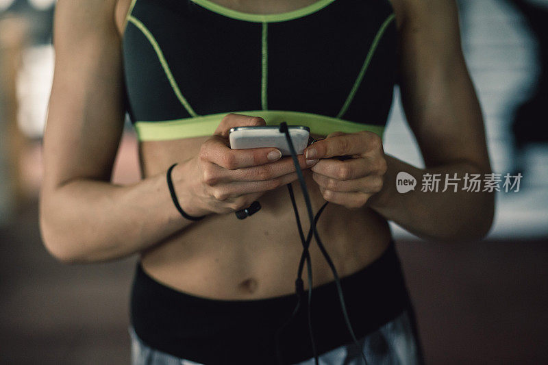 一个女人在健身房锻炼时玩智能手机