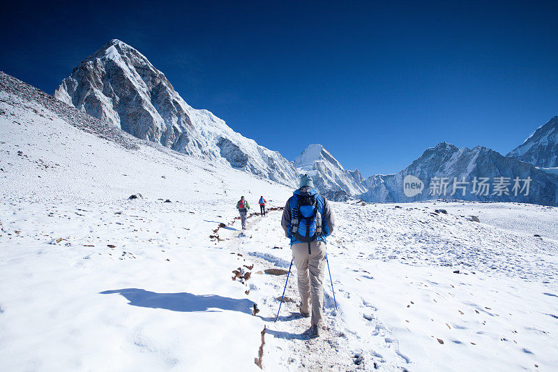 徒步旅行者穿过积雪走向希马的山峰