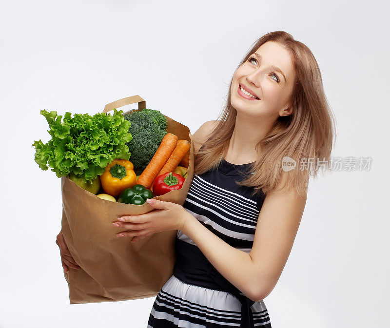 快乐的女人拿着装着健康素食的购物袋