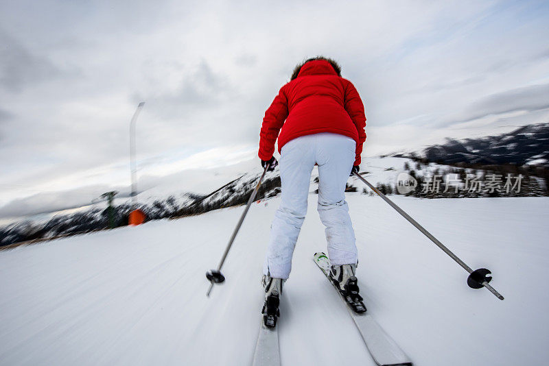 一个无忧无虑的滑雪者在模糊运动滑雪的后视图。