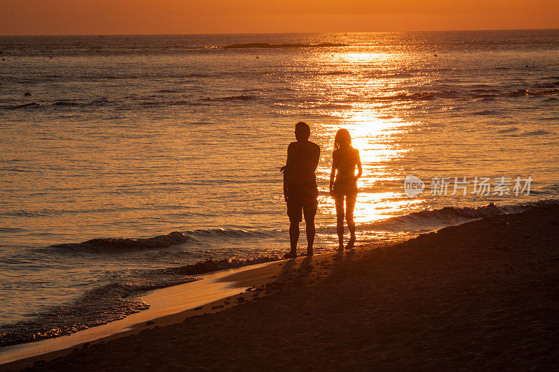 在海边散步的夫妇在日落时的剪影