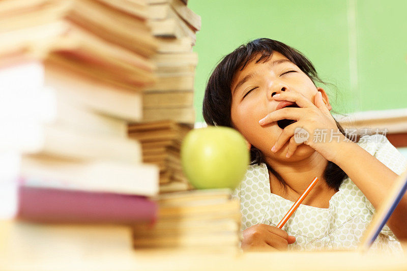 疲惫的年轻亚洲女学生打哈欠在学习时间
