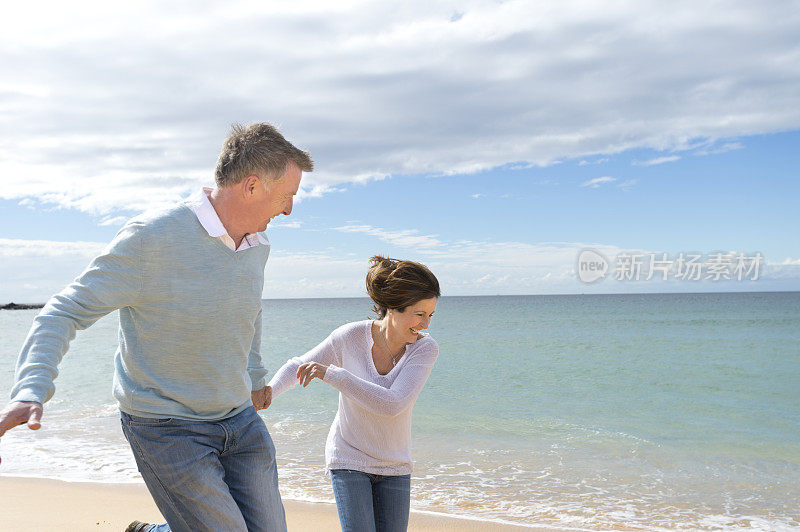 一对快乐成熟的情侣在海滩上跑步