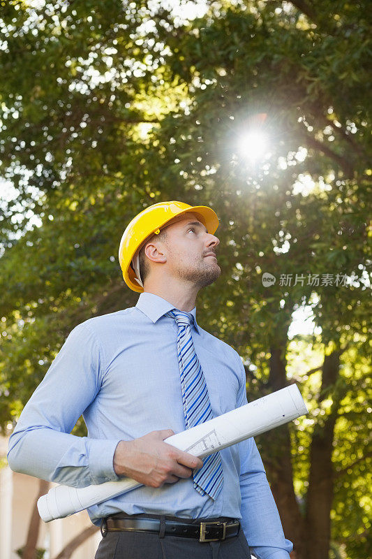 年轻的男建筑师带着蓝图在户外