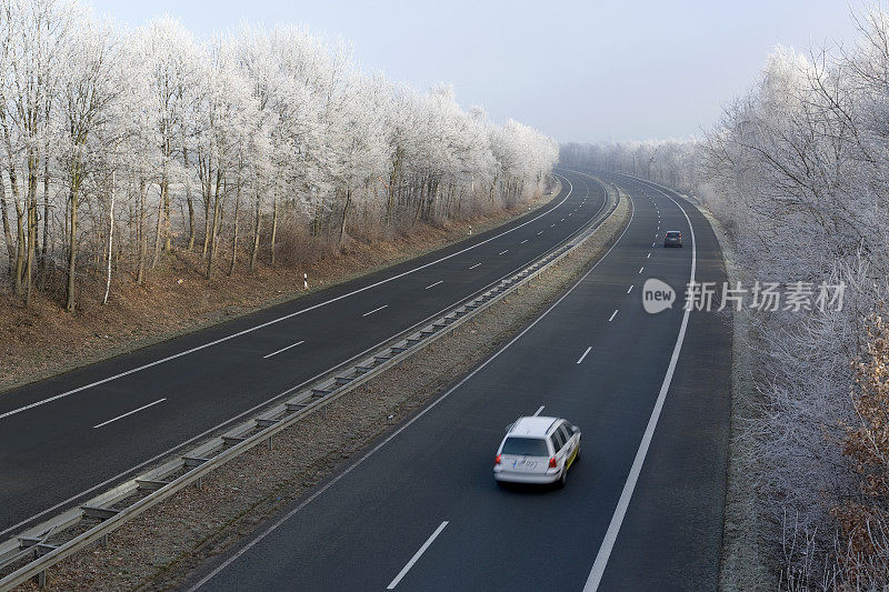 在冬天，两车道的高速公路上有一辆白色的汽车