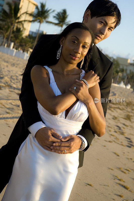 异族婚礼夫妇在海滩上摆姿势