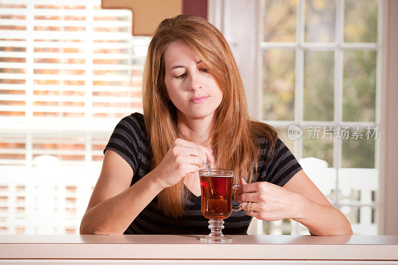 忧伤的女人一边搅茶一边低头看