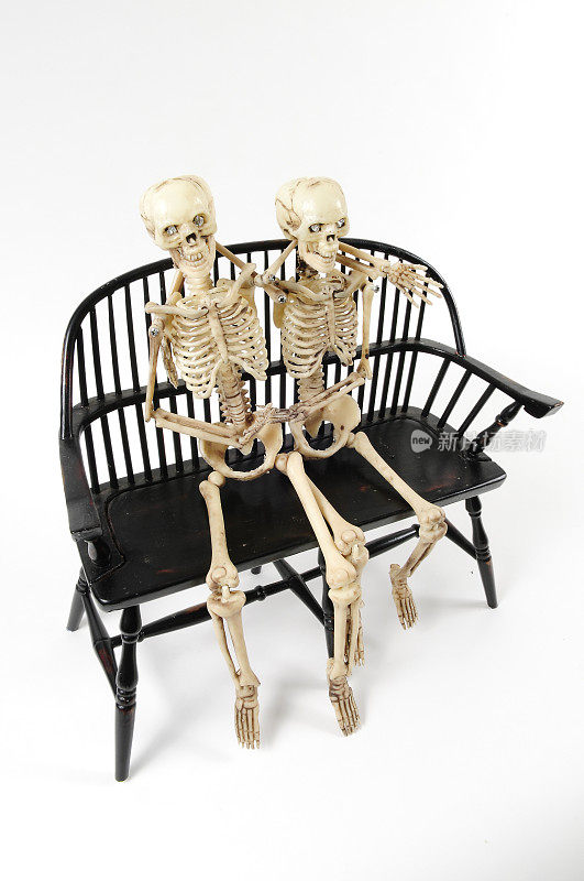 两具骨架坐在一把古董木椅上