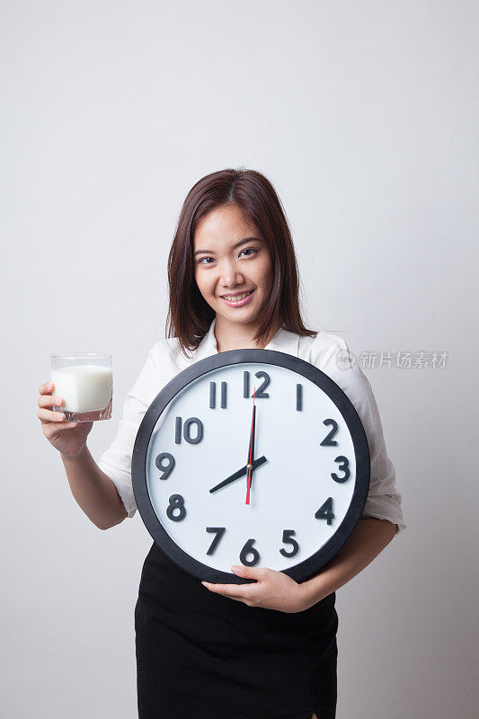 健康的亚洲女人喝牛奶抱钟。