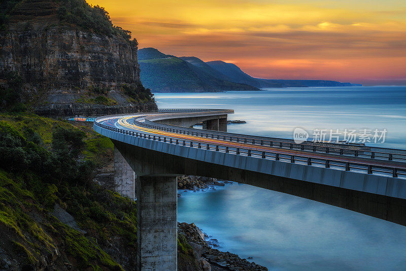 日落在海上悬崖桥沿澳大利亚太平洋海岸与过往的汽车灯光