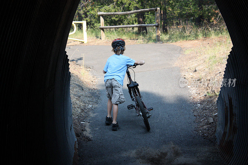 男孩推着自行车穿过隧道