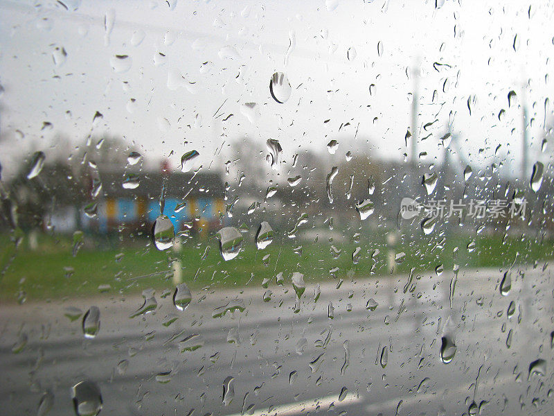 汽车玻璃滴路。窗外的大雨以城市、村庄为背景。
