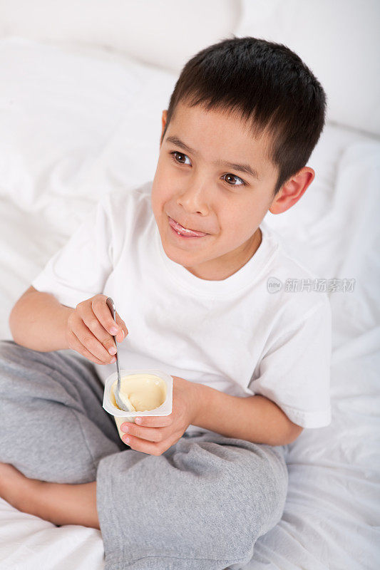 小男孩在床上吃酸奶