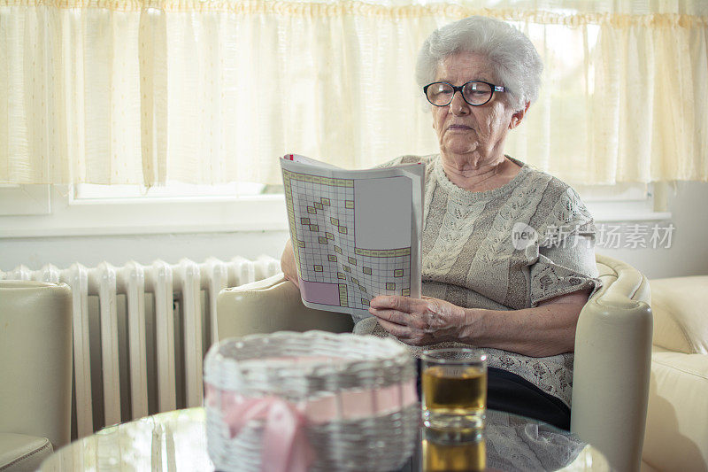 老女人在家玩填字游戏。