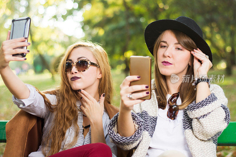 女孩们在长凳上玩手机