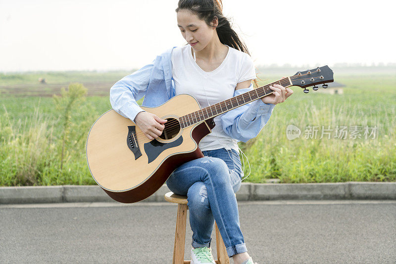 在草地上弹吉他的时尚女人