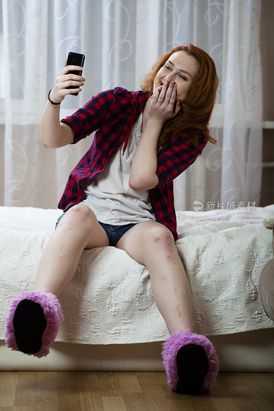 坐在床上玩智能手机的女孩