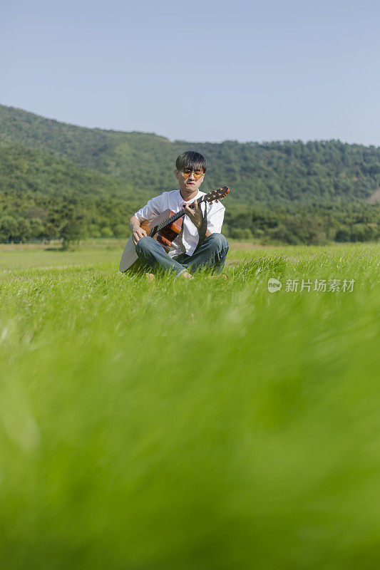 一个年轻人在草坪上弹原声吉他