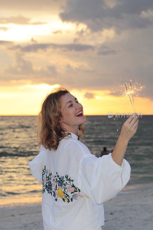 夕阳西下的海滩上，一个年轻女子带着烟火。