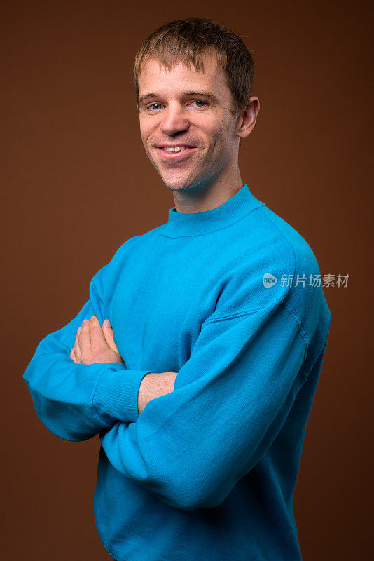 在彩色背景下，一名男子穿着蓝色毛衣