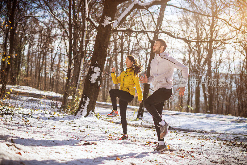 侧面的年轻的动机，有吸引力的健身活跃的夫妇在冬季运动服温暖在雪林。