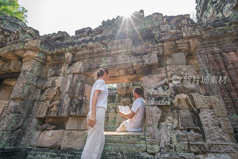 年轻夫妇一边阅读旅游指南一边参观古庙，人们在旅游目的地发现团聚的概念