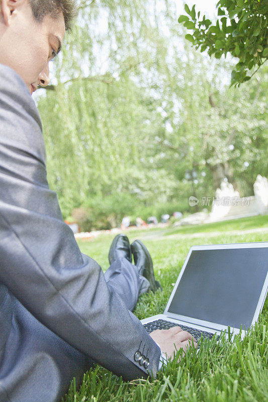中国商人在公园里使用笔记本电脑
