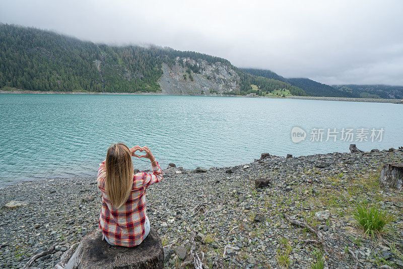 一个热爱自然的少女，在山湖上做心形的指架