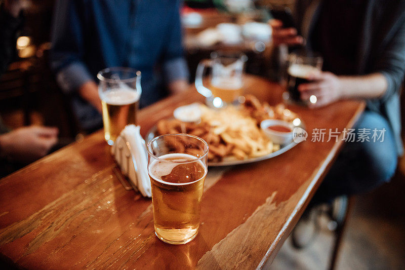 俯视图上的手指食物和苍白的啤酒在一个酒吧的桌子上