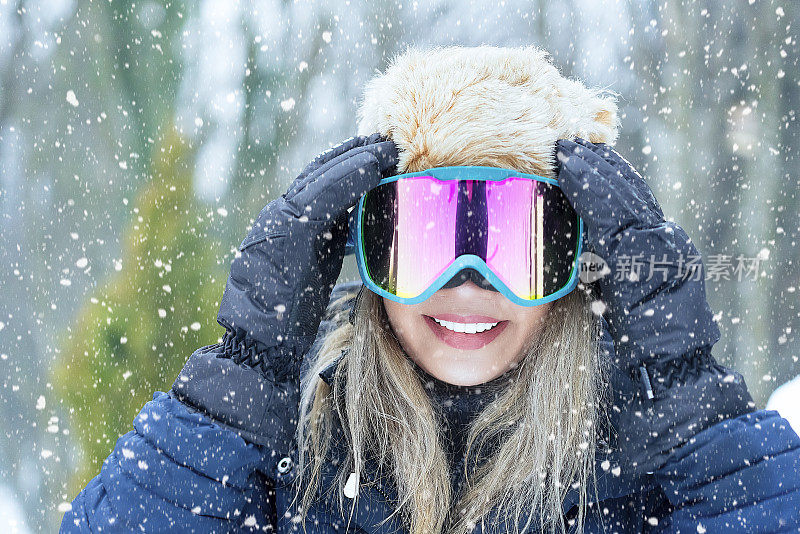 在大自然中戴着滑雪眼镜的女性单板滑雪运动员的肖像