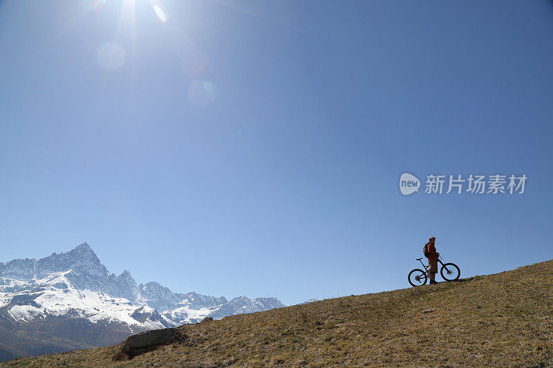 男性山地自行车下山岩石在草山上