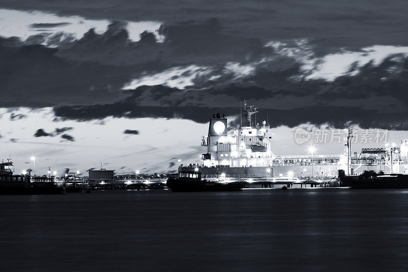 黑色和白色海湾的水在晚上与油轮在炼油厂港口，背景与拷贝空间