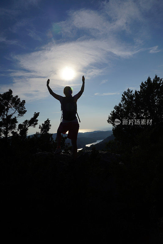 克罗地亚Mljet岛的大湖上，一名老妇人向太阳举起双手