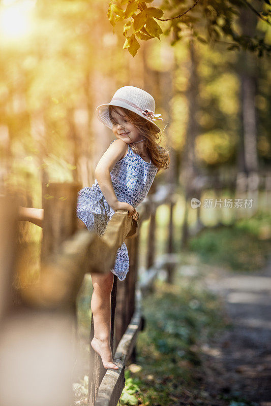 快乐的小女孩站在篱笆上