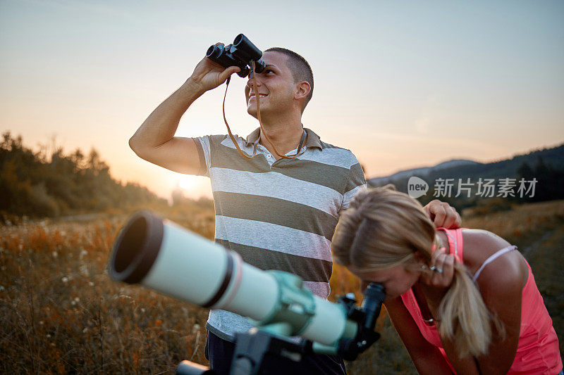 青年男女用望远镜和双筒望远镜看天空。