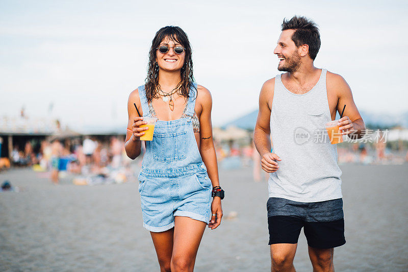 年轻夫妇在海滩上享用鸡尾酒