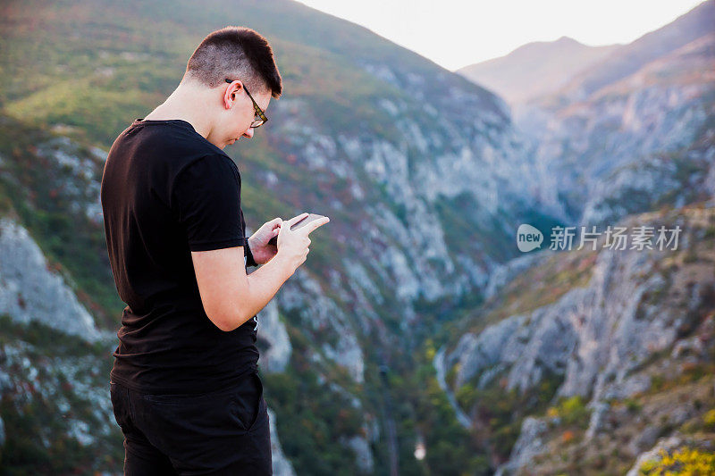 一个拿着手机站在山上的男人