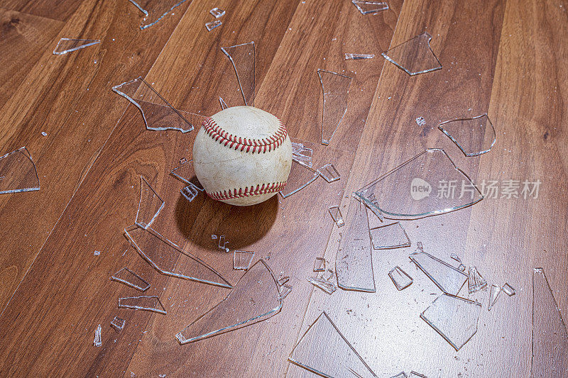 从地板上的一扇窗户往下看一个有碎玻璃的棒球