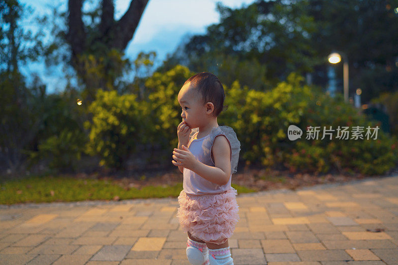 一个蹒跚学步的孩子和她晚上在户外公园的小探索