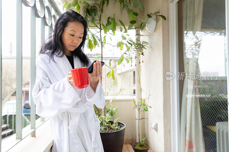 一个日本女人在阳台上看智能手机