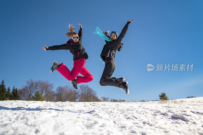 年轻的滑雪者在雪山上嬉戏跳跃