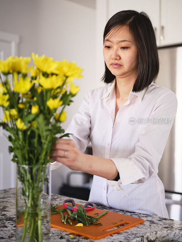 亚洲妇女在她的家里插花