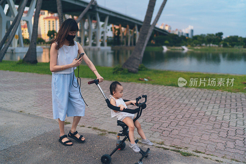 在冠状病毒大流行时，亚洲母亲在户外拍摄她的孩子